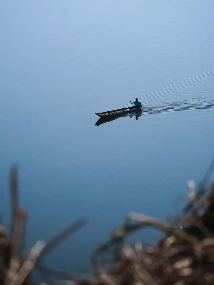 A lone paddler crossing the open lake in a dugout canoe