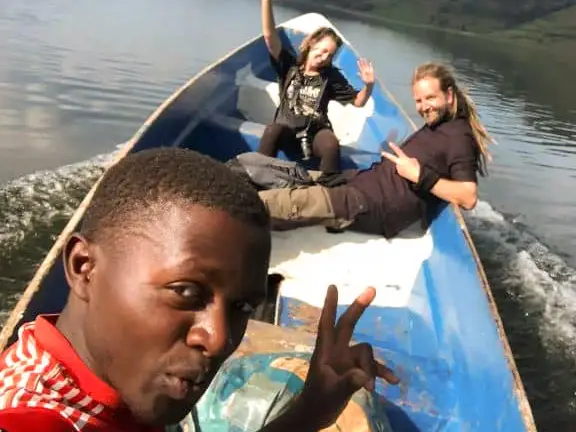 Guests waving from a motorboat crossing the lake